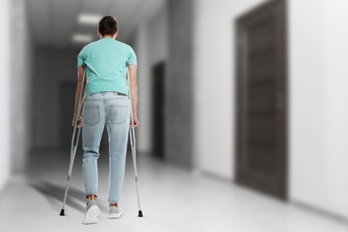 Image of Man with axillary crutches in hospital, back view. Space for text