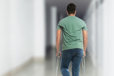 Image of Man with axillary crutches in hospital, back view