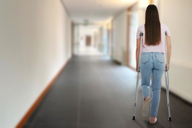 Image of Woman with axillary crutches in hospital, back view. Space for text