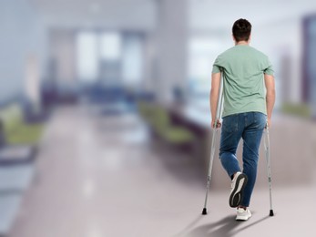 Image of Man with axillary crutches in hospital, back view. Space for text