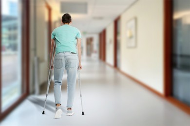 Image of Man with axillary crutches in hospital, back view. Space for text