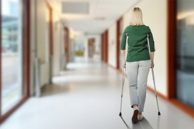 Image of Woman with axillary crutches in hospital, back view. Space for text