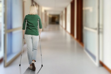 Image of Woman with axillary crutches in hospital, back view. Space for text
