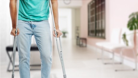 Image of Man with axillary crutches in hospital, closeup. Banner design