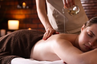Photo of Woman receiving back massage with oil in spa salon, closeup