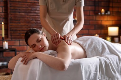 Photo of Woman receiving back massage with oil in spa salon