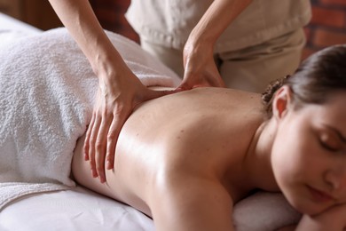 Photo of Woman receiving back massage with oil in spa salon, closeup