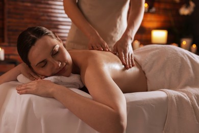 Photo of Woman receiving back massage with oil in spa salon