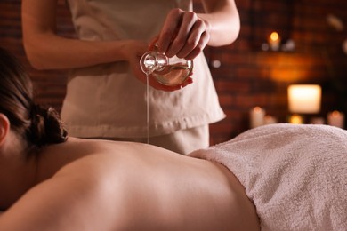 Photo of Woman receiving back massage with oil in spa salon, closeup