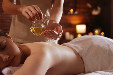 Photo of Woman receiving back massage with oil in spa salon, closeup
