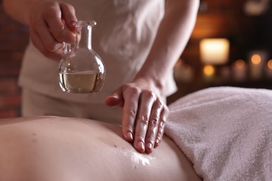 Photo of Woman receiving back massage with oil in spa salon, closeup