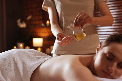 Photo of Woman receiving back massage with oil in spa salon, closeup