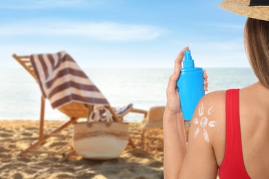 Image of Woman with bottle of sun protection spray on beach, closeup. Sun image made with sunblock cream on her shoulder