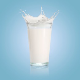 Image of Milk splashing out of glass on light blue background