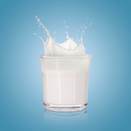 Image of Milk splashing out of glass on light blue background