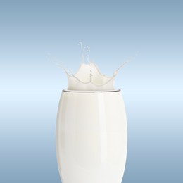 Image of Milk splashing out of glass on light greyish blue background