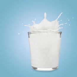 Image of Milk splashing out of glass on light blue background