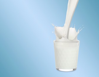 Image of Pouring fresh milk into glass against light blue background. Liquid splashing out of glass