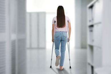 Image of Woman with axillary crutches in hospital, back view