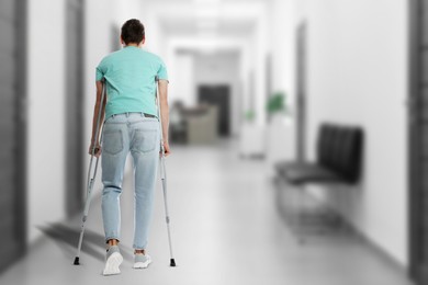 Image of Man with axillary crutches in hospital, back view. Space for text
