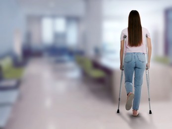 Image of Woman with axillary crutches in hospital, back view. Space for text