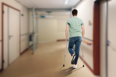 Image of Man with axillary crutches in hospital, back view. Space for text