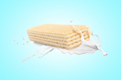 Image of Tasty crispy wafer and milk splash on light blue background
