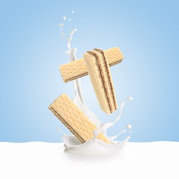 Image of Tasty crispy wafers falling into splashing milk against light blue background