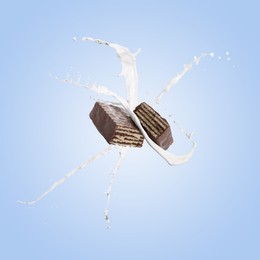 Image of Tasty crispy wafer and splashing milk on light blue background