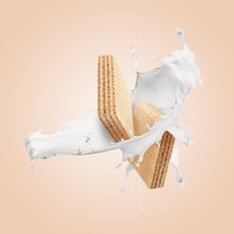 Image of Tasty crispy wafers and splashing milk on pink beige background