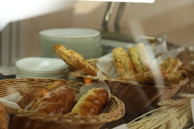 Photo of Wicker baskets with tasty food in school canteen, closeup
