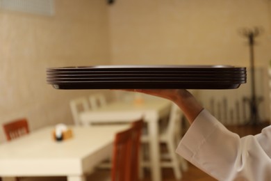 Photo of School canteen worker holding plastic trays for food indoors, closeup