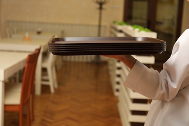 Photo of School canteen worker holding plastic trays for food indoors, closeup