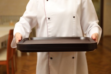 Photo of School canteen worker holding plastic trays for food indoors, closeup