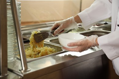 Photo of School canteen worker at serving line, closeup. Tasty food