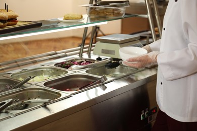 Photo of School canteen worker at serving line, closeup. Tasty food