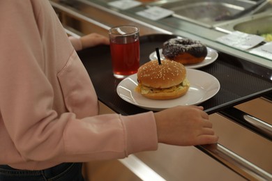 Photo of Little girl with plastic tray near serving line in canteen, closeup. School food