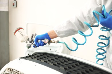 Photo of Worker painting car in body shop, closeup