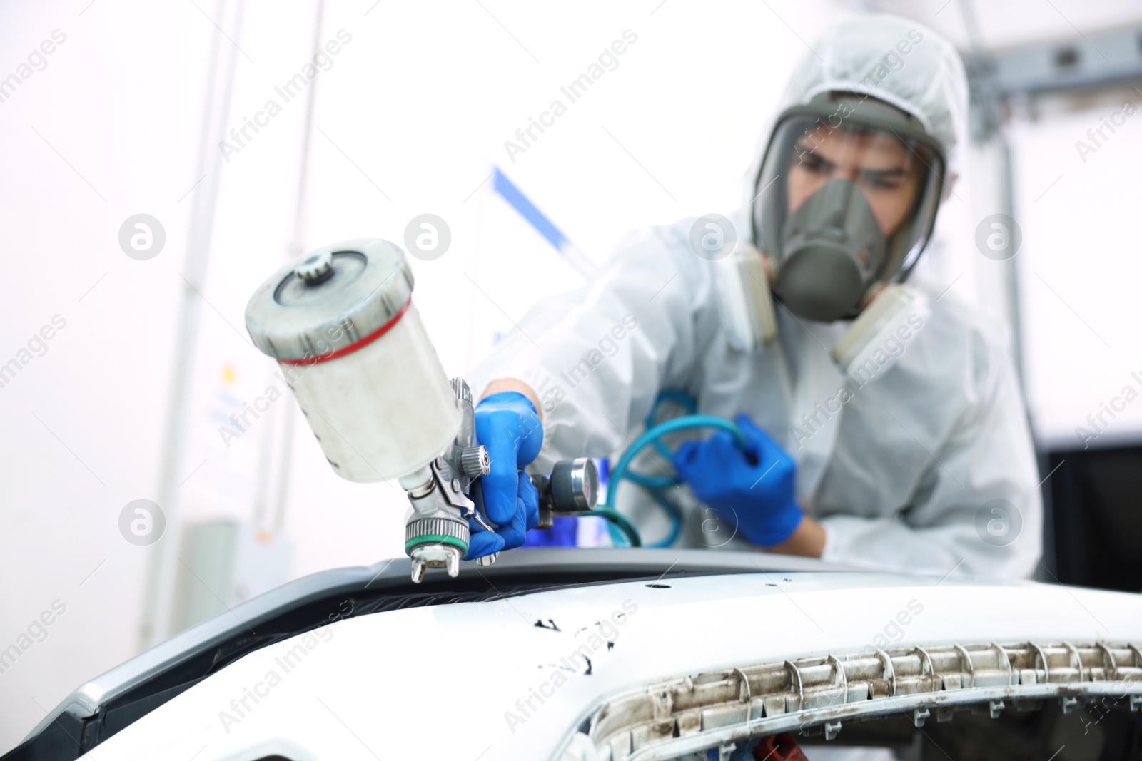 Worker painting car in body shop, selective focus Photo of Worker painting car in body shop, selective focus