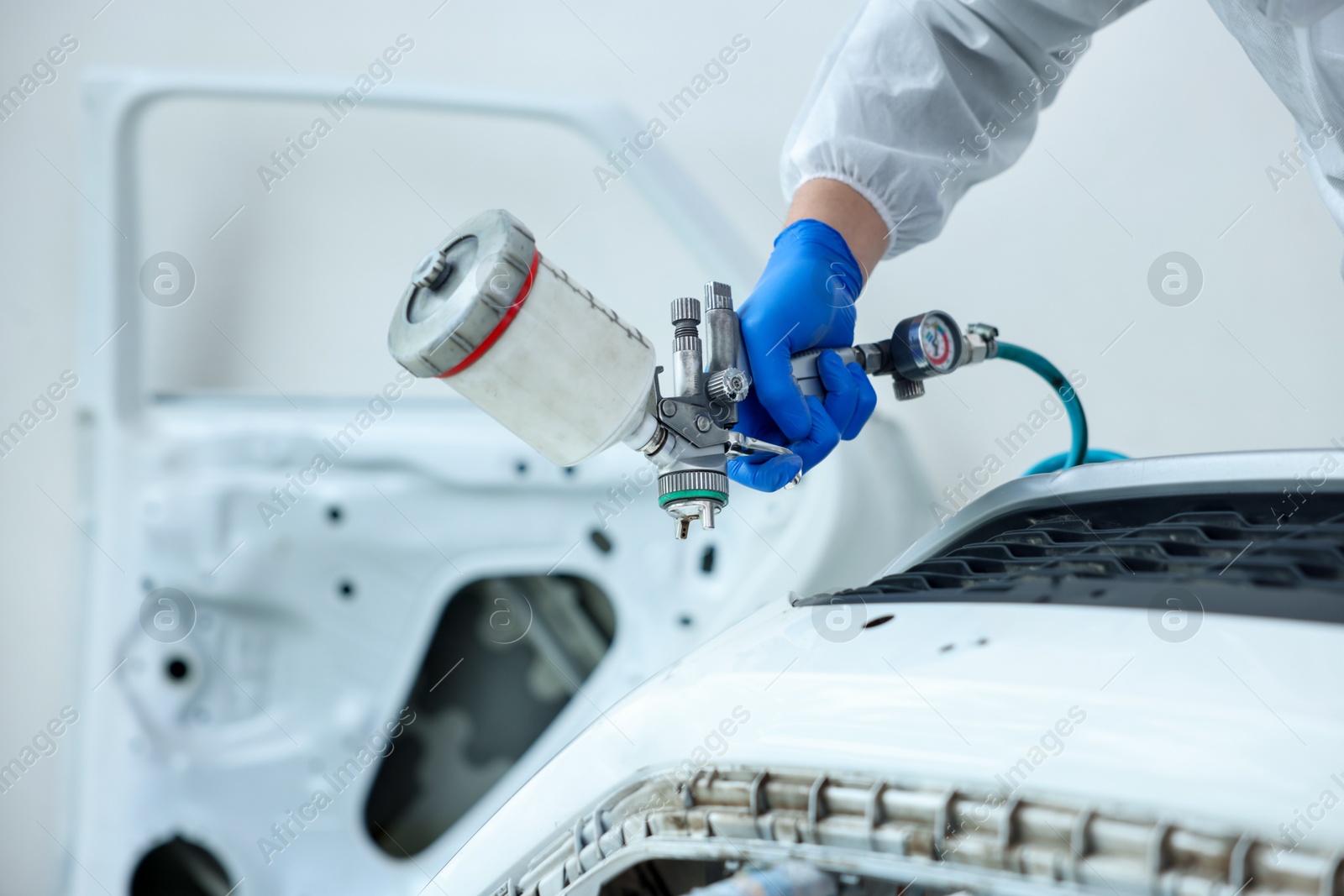 Worker painting car in body shop, closeup Photo of Worker painting car in body shop, closeup