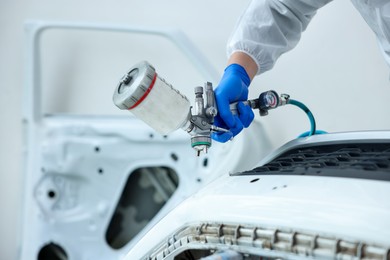 Photo of Worker painting car in body shop, closeup