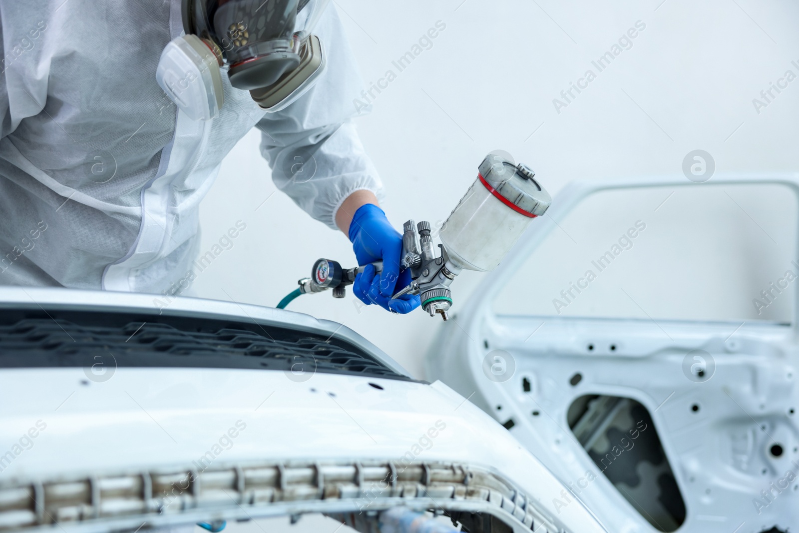 Photo of Worker painting car in body shop, closeup