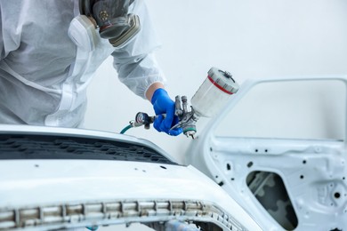 Photo of Worker painting car in body shop, closeup