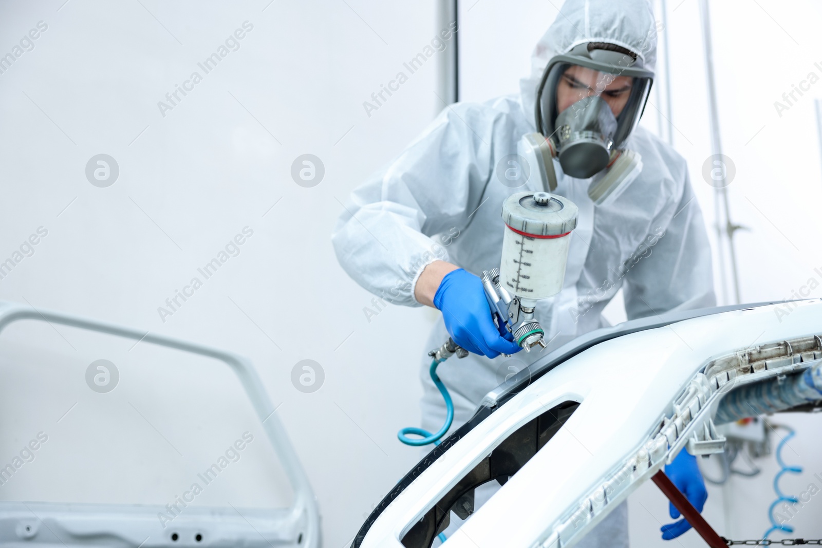 Worker spray painting car in body shop. Space for text Photo of Worker spray painting car in body shop. Space for text
