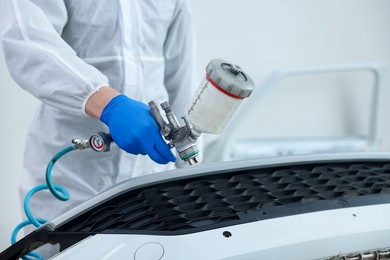 Photo of Worker painting car in body shop, closeup