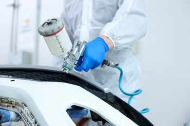 Photo of Worker painting car in body shop, closeup