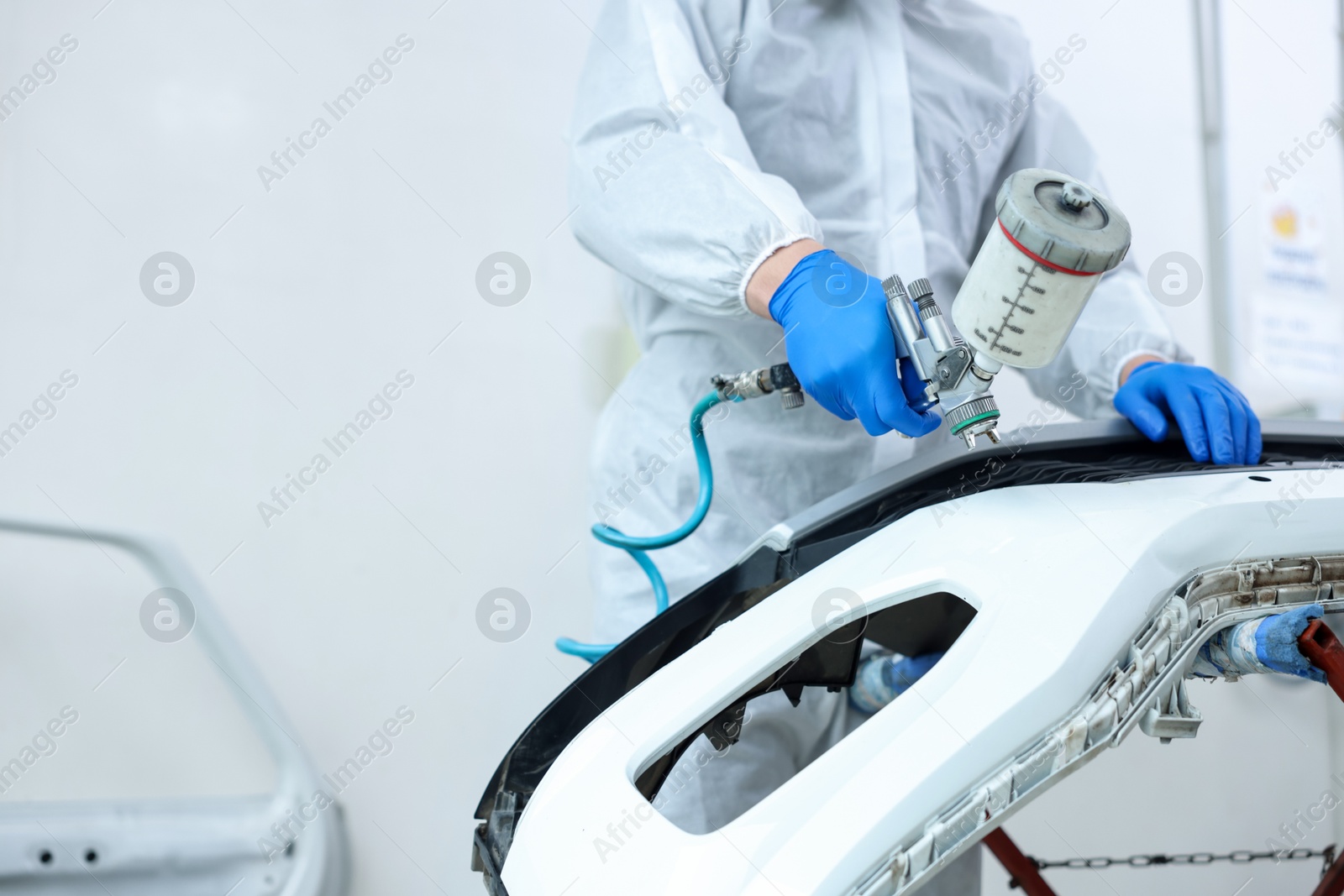Worker painting car in body shop, closeup. Space for text Photo of Worker painting car in body shop, closeup. Space for text