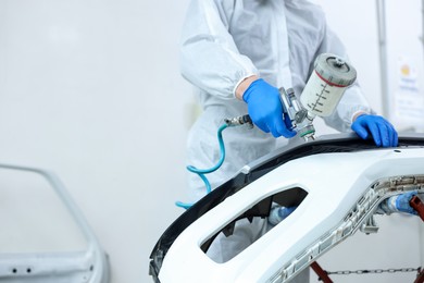 Photo of Worker painting car in body shop, closeup. Space for text