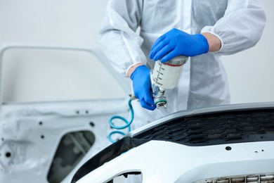 Photo of Worker painting car in body shop, closeup