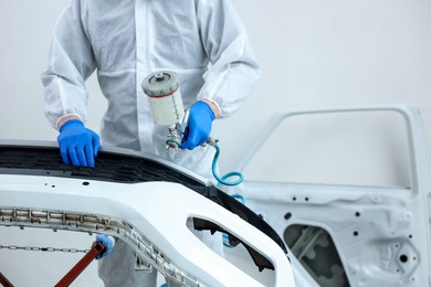 Photo of Worker painting car in body shop, closeup